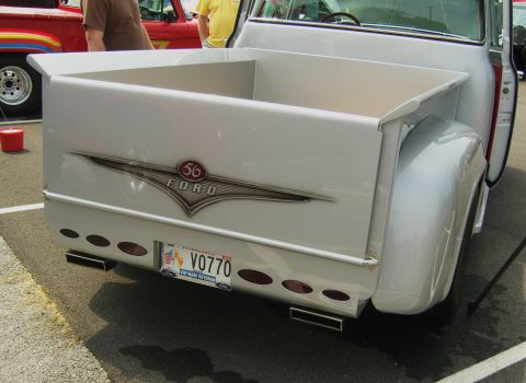 2007 Ford Mustang - Rear view of a classic 1956 Ford pickup truck, showing the tailgate and custom exhaust pipes.