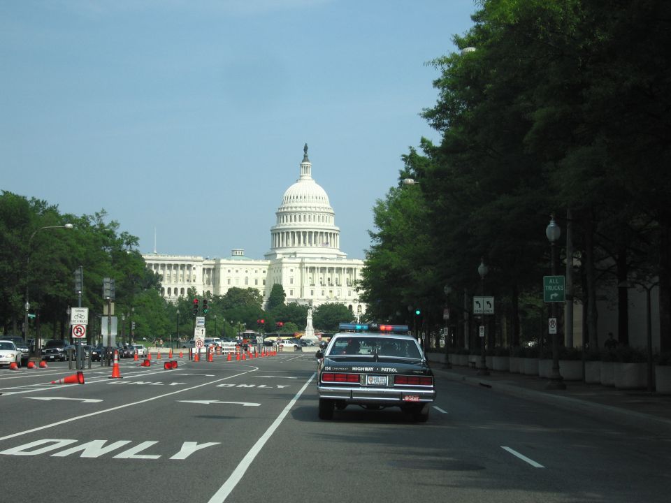 Patrol car driving toward the U.S. Capitol on a city avenue