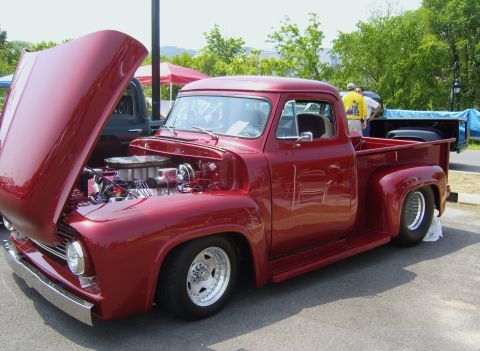 2007 Ford Mustang - A custom red 1953 Ford F-100 pickup truck is displayed with its hood open, the engine bay.