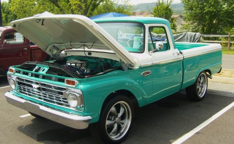2007 Ford Mustang - A turquoise and white 1965 Ford F-100 pickup truck is parked with its hood open, revealing the engine bay.