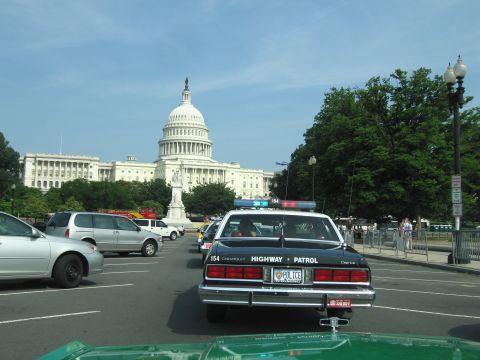 1991 Ford Crown Victoria - Police car with lights on parked near the US Capitol building on a sunny day.