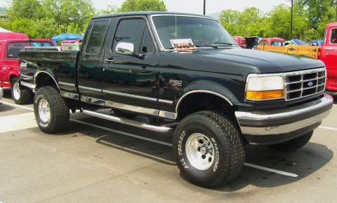 2007 Ford Mustang - A black Ford F-150 pickup truck is parked at an outdoor event, with other vehicles visible in the background.