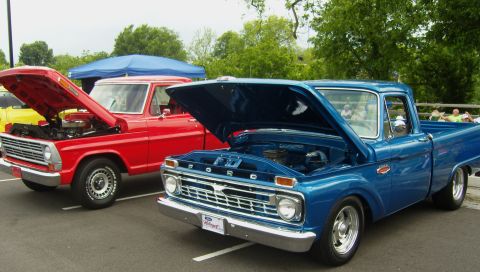 2007 Ford Mustang - Two classic Ford pickup trucks are displayed with their hoods open at an outdoor event.