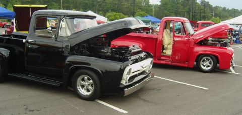 2007 Ford Mustang - Two classic pickup trucks, one black and one red, are displayed with their hoods open at an outdoor event.
