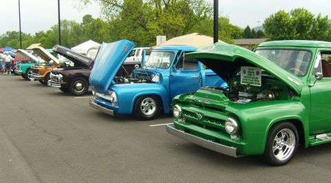 2007 Ford Mustang - A line of classic trucks are displayed with hoods open at a car show. The green truck in the foreground is a 1956 Ford F-100.