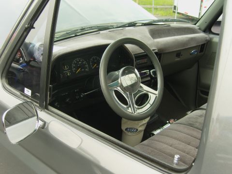 2007 Ford Mustang - The interior of a gray truck shows an aftermarket steering wheel and dashboard gauges, with an NHRA hat visible on the floor.