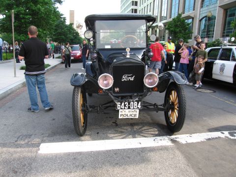 1991 Ford Crown Victoria - A vintage black Ford Model T, marked as a police vehicle, is parked on a street with onlookers.