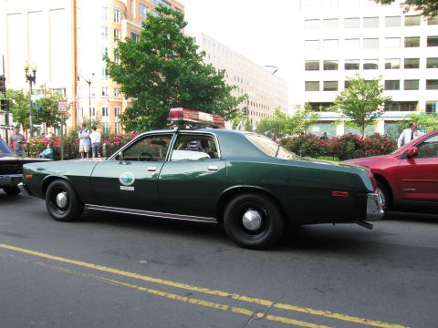 1991 Ford Crown Victoria - A dark green sedan, possibly a police vehicle, is parked on a street with buildings in the background.