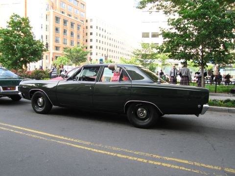 1991 Ford Crown Victoria - A dark sedan, likely from the early 1970s, is parked on a city street.