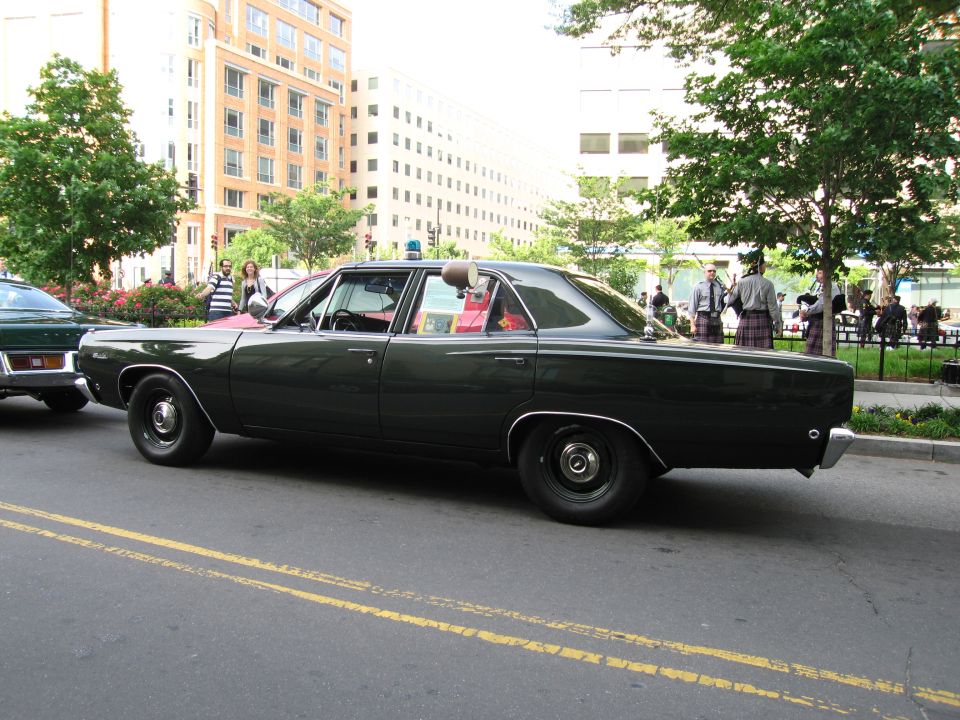 Dark green vintage four-door police sedan, side profile on city street