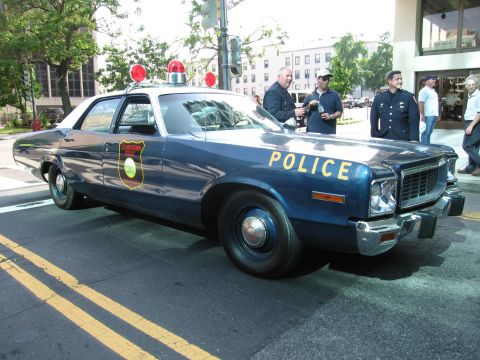 1991 Ford Crown Victoria - A vintage police car is parked on a street with several officers standing nearby.