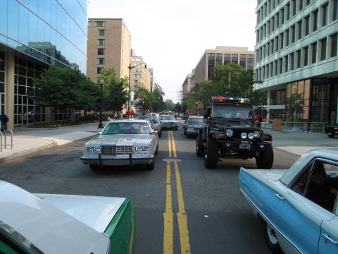 1991 Ford Crown Victoria - A silver sedan, likely from the 1980s, is seen in traffic on a city street, with a modified Jeep and other vehicles around it the backgroun…
