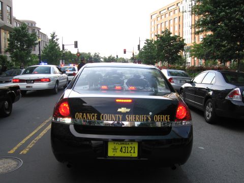1991 Ford Crown Victoria - Several police vehicles are stopped in traffic on a city street.