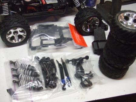 1996 Ford Bronco - Various parts for an RC car are organized on a surface, including a chassis and spare tires.