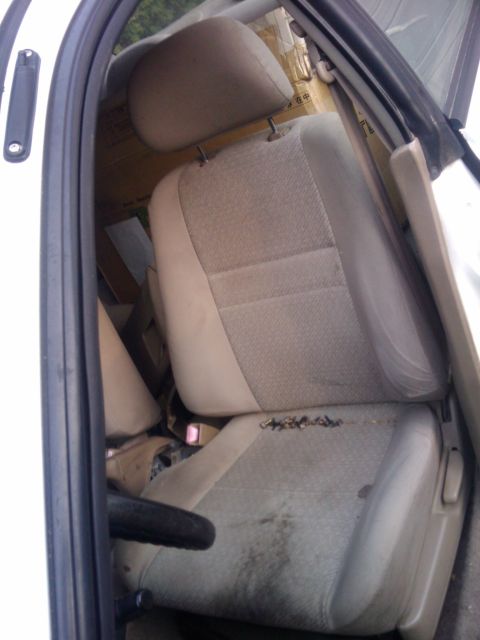 1998 Subaru Legacy - The interior of a car shows worn seats and boxes piled up behind them.
