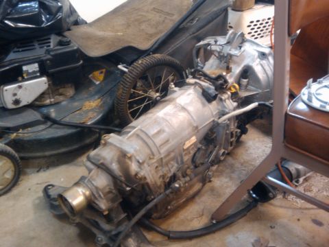 1998 Subaru Legacy - A transmission part is visible on the floor next to a lawnmower and a chair.