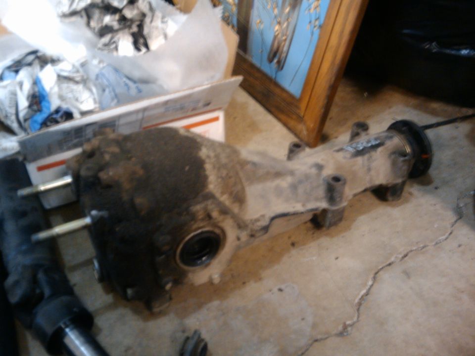 Differential housing with some grease and dirt, resting on a concrete floor