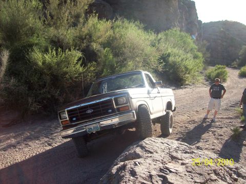 1985 Ford Bronco - A lifted Ford F-Series truck navigates a rough, off-road path.