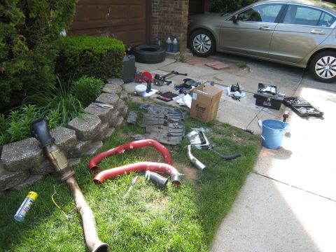 2007 Subaru Impreza - Various car parts, including exhaust components and tools, are spread across the lawn.