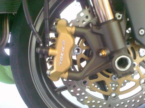 2005 Kawasaki Ninja R - Close-up of a gold Tokico brake caliper and rotor assembly on a motorcycle wheel.