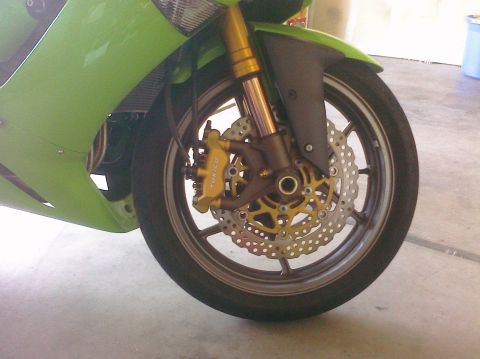 2005 Kawasaki Ninja R - Close-up of a motorcycle's front wheel assembly, showing the brake system and suspension components.