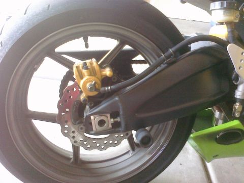 2005 Kawasaki Ninja R - The rear wheel assembly of a motorcycle is shown, the brake disc and caliper.