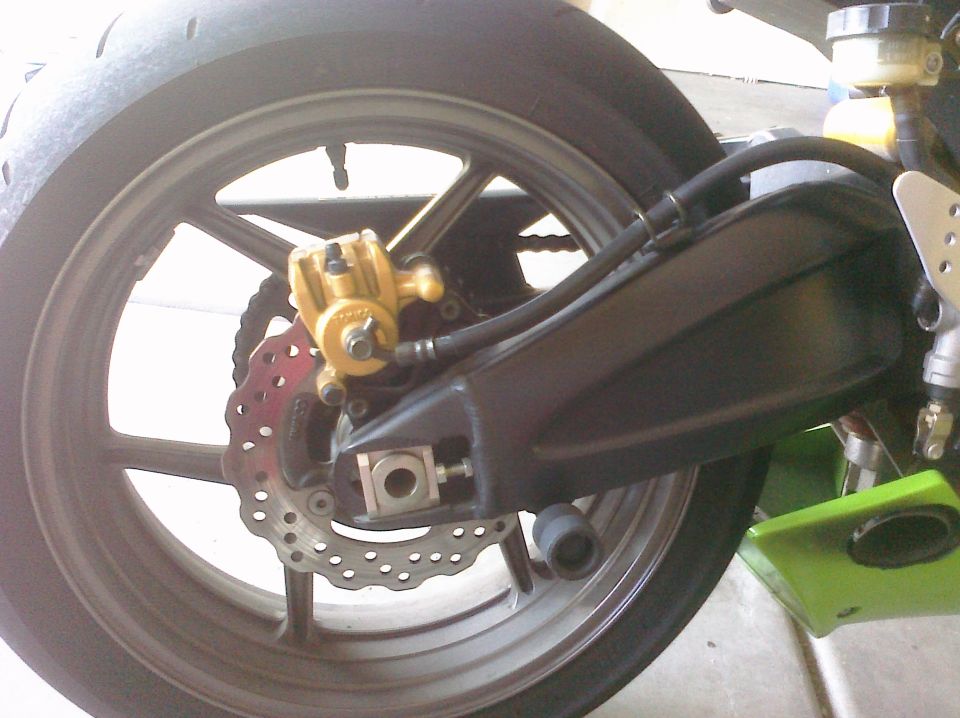 close up of motorcycle rear wheel, brake caliper, and chain guard