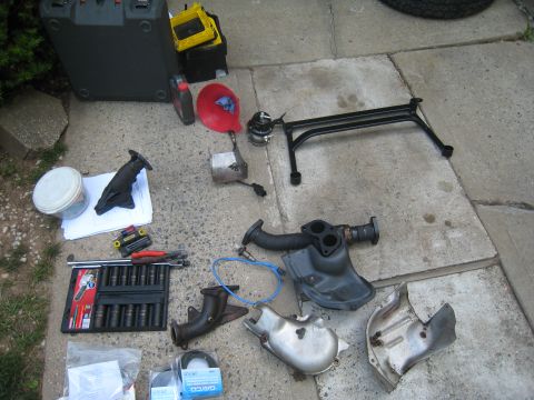 2007 Subaru Impreza - Various automotive exhaust components, including a TiAL 44mm external wastegate, are laid out on a concrete surface.