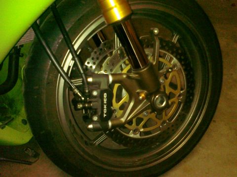 2005 Kawasaki Ninja R - Close-up of a motorcycle's front wheel assembly, showing the brake system and suspension components.