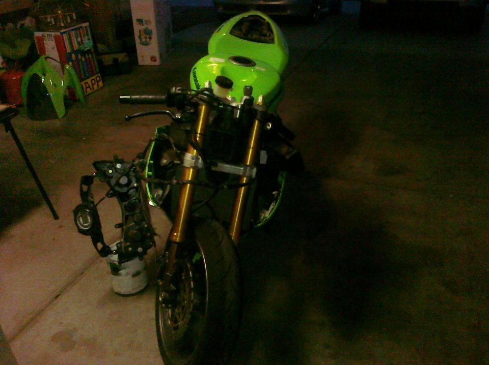 Green Kawasaki Ninja R motorcycle, front view, disassembled with front forks and engine components visible