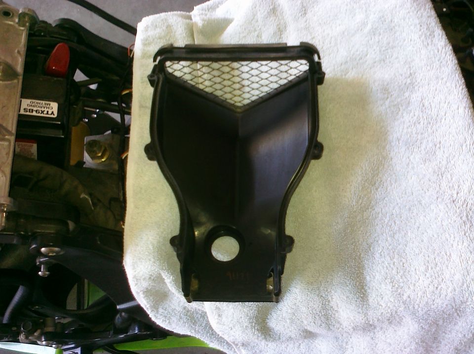 Black plastic motorcycle air intake cover with mesh screen, resting on a white towel