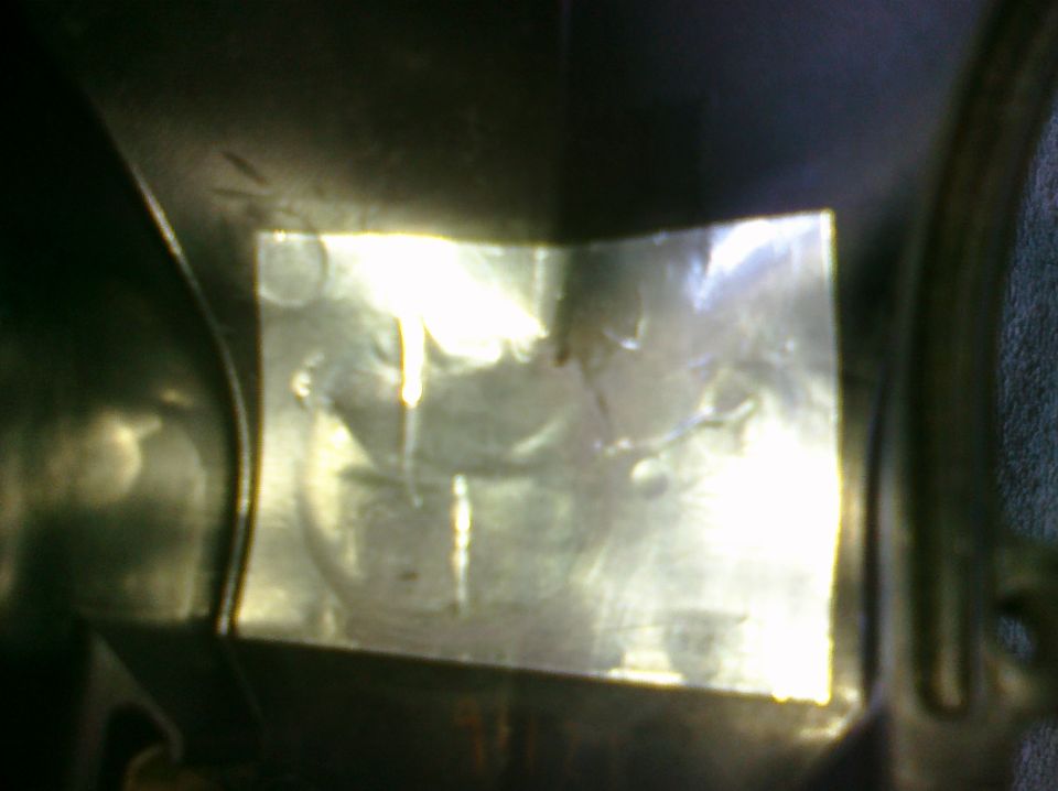 Close-up of a shiny metal part on a motorcycle, possibly a cover or fairing piece