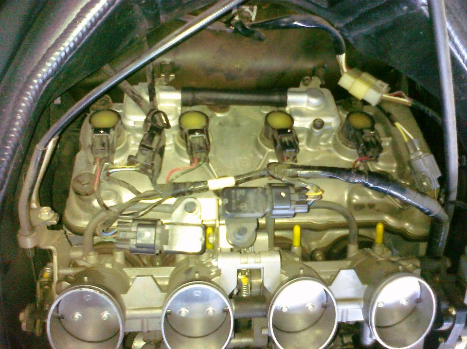 Close-up of motorcycle engine throttle bodies and ignition coils with wiring