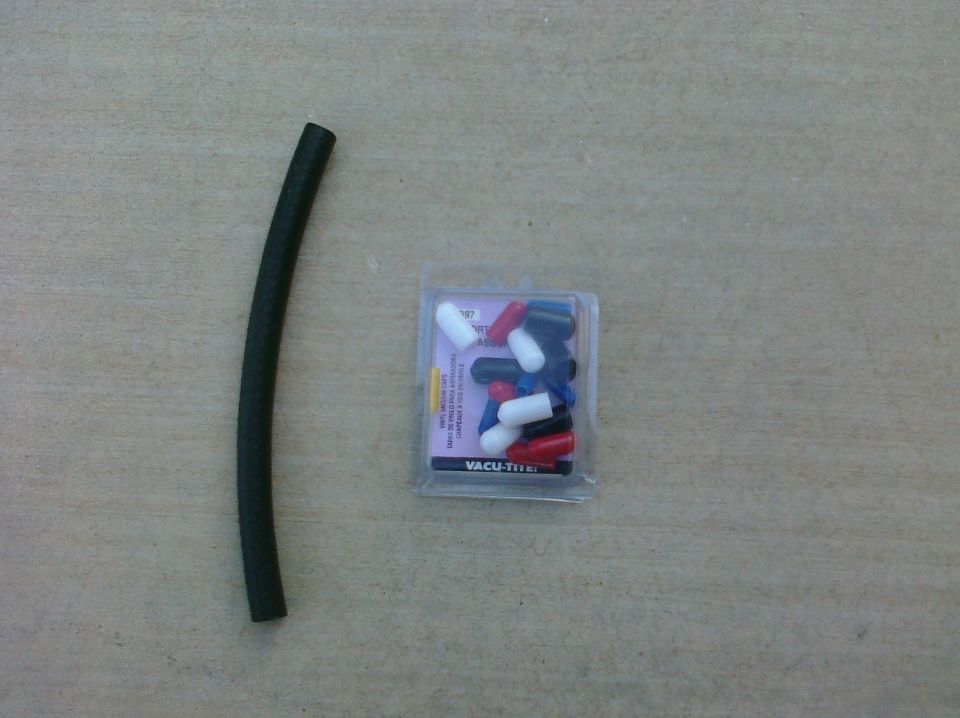 Black rubber hose and a package of assorted colored vacuum caps on a textured surface