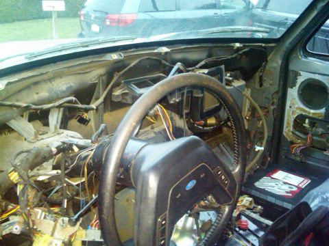 1986 Ford Bronco - The interior of a vehicle is shown with the dashboard disassembled, revealing exposed wiring and components.