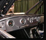 1986 Ford Bronco - Interior view of a vehicle's dashboard a custom gauge cluster and roll cage structure.