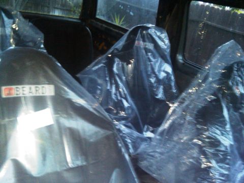 1986 Ford Bronco - The interior of a vehicle shows seats covered in protective plastic, with a visible "BEARDE" label on one.