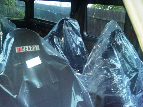 1986 Ford Bronco - Interior view of a vehicle showing three plastic-covered seats, one with a BEARD TEAM label.