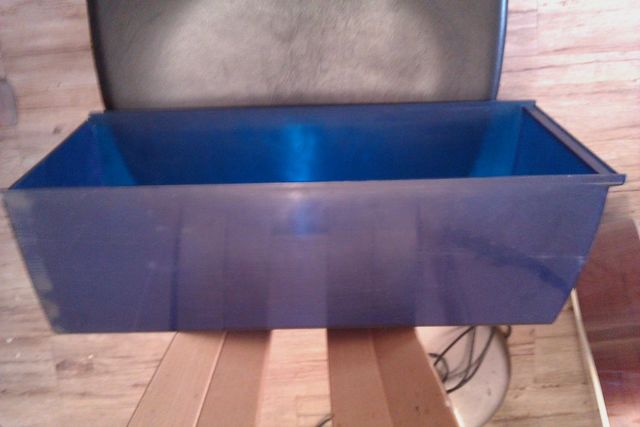 Blue plastic bin on wooden surface, part of a seat visible above
