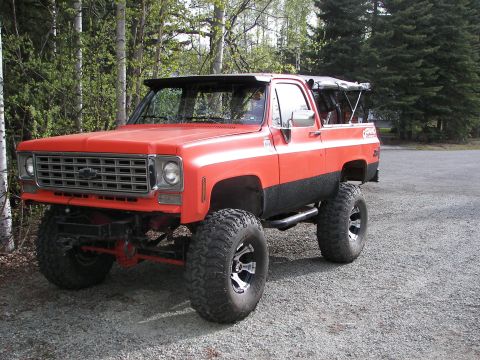 1990 Chevrolet Suburban - This lifted orange Chevrolet K5 Blazer is equipped with large off-road tires and black trim.