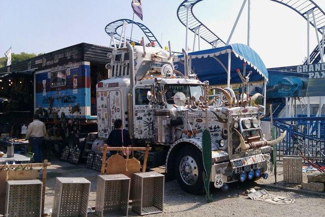 Customized semi-truck with steer horns, decals, and a roller coaster in the background