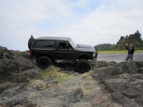 1996 Ford Bronco - A black Ford Bronco navigates a rocky coastal path with two people visible in the background.