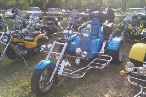 1991 Ford LTD Crown Victoria - A blue trike motorcycle is parked among other vehicles and motorcycles on a grassy area.