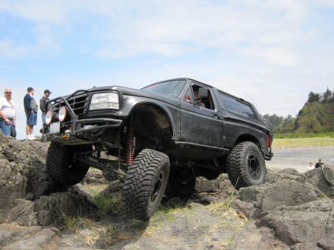 1996 Ford Bronco - Modified black Ford Bronco tackles a challenging rocky coastal path.