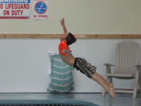 1996 Ford Bronco - A boy leaps into a swimming pool, with safety signs posted on the wall above.