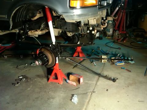 1994 Ford Bronco - Front suspension components are laid out on the garage floor as work is performed on the vehicle.