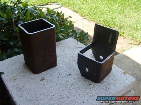 1994 Ford Bronco - Two fabricated metal brackets sit on a concrete surface outdoors, with greenery in the background.
