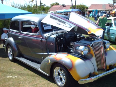 1992 Ford Bronco - A customized sedan with flame paint is displayed with its hood open at an outdoor event.