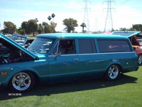 1992 Ford Bronco - A teal station wagon is parked on a grassy field with its hood open, under a bright sky.
