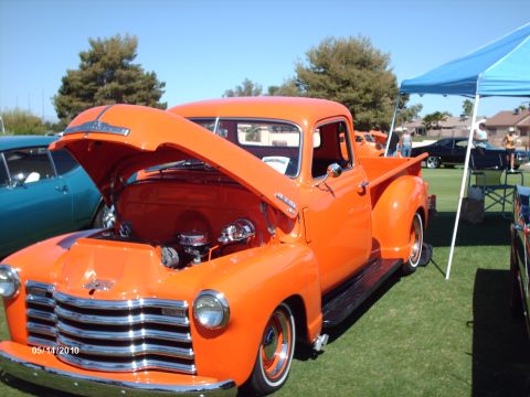 1992 Ford Bronco - Orange 1950 Chevrolet pickup truck on display at a car show, with hood open.